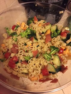 a glass bowl filled with pasta and vegetables