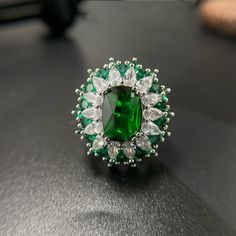 an emerald and diamond ring on a table