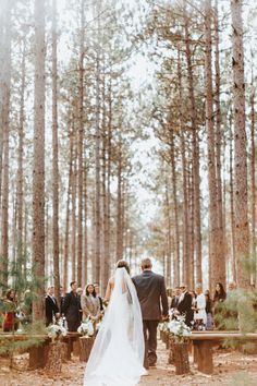 a bride and groom walking down the aisle at their outdoor wedding ceremony in the woods