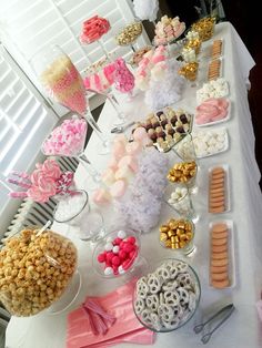 an assortment of candy and candies on a long table with white tablescloths