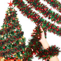 a christmas tree is decorated with red and green ornaments, while a hand reaches up to grab the ribbon