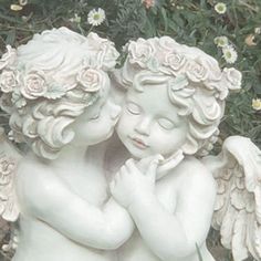 two white cherubs hugging each other in front of flowers