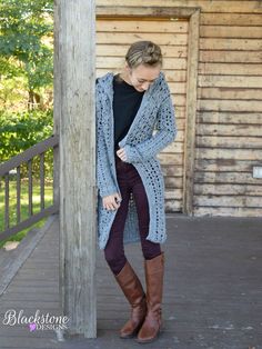 a woman standing on a porch wearing boots and a cardigan sweater over her shoulders