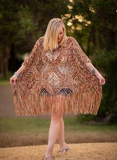 a woman is standing in the grass with a shawl on her shoulders and legs