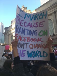 a person holding up a sign that reads i march because ranting on facebook don't change the world