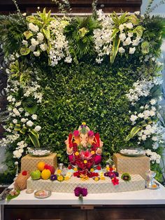 an arrangement of flowers and fruit on a table with a ganesh idol in the middle