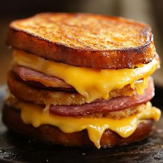 a grilled cheese and ham sandwich is on a black plate, ready to be eaten