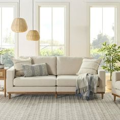 a living room with two couches, chairs and a rug in front of windows