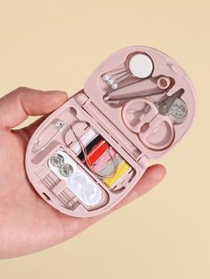 a pink manicure kit in someone's hand with scissors and other items inside