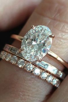 a close up of a person's hand with a ring on it and an oval shaped diamond in the middle