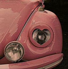 the front end of an old pink car with a heart on it's grill