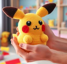 a hand holding a small crocheted pikachu