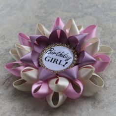 "Planning a birthday party? This handmade pin can be customized in your colors! You are welcome to leave a note during checkout regarding any color changes. Please see the chart in the pictures for all available ribbon colors. The pin shown is made from Ivory, Bubblegum and Thistle satin ribbon with a gold and crystal framed centerpiece. Each pin is 3 1/2\" wide and comes packaged in a cotton lined gift box with bow. See more birthday items here: http://www.etsy.com/shop/PetalPerceptions/search? Purple Pink And Silver Birthday Party, Party Pins With Bow, Diy Birthday Ribbon Pin, Pink Birthday Sash, Birthday Ribbon Pin, Personalized Centerpieces, Birthday Pins, Birthday Items, Purple Birthday