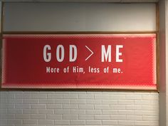 a red sign that says god / me more of him, less of me hanging on the wall