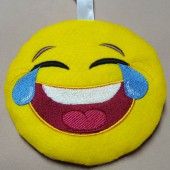 a yellow smiley face ornament hanging from a white ribbon on a gray surface