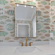 a bathroom sink with a mirror above it and fish wallpaper on the wall behind it