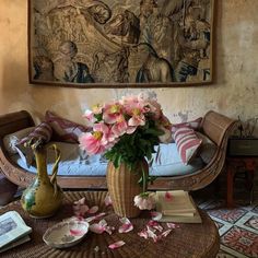 pink flowers in a vase on a wicker coffee table with plates and other items