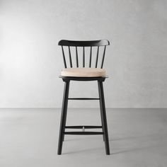 a black chair with a beige seat and backrest in front of a white wall