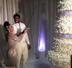 a man and woman are standing in front of a cake with white frosting on it