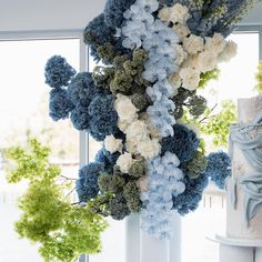 blue and white flowers are hanging from the side of a tall pillar in front of a window