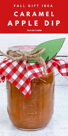 a jar filled with caramel apple dip on top of a white wooden table next to a red and white checkered ribbon