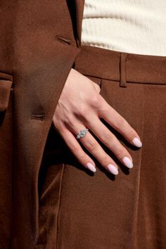 a woman's hand with a ring on her left wrist, wearing brown pants and a white top