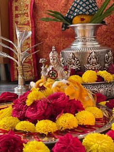 there are many flowers in front of the buddha statue and other decorations on the table