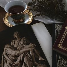 a cup of tea sitting on top of a table next to books and a statue