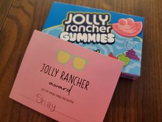 a pink sticky note sitting on top of a wooden table next to a box of gummy