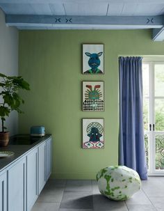 a living room with green walls and pictures on the wall next to a large window