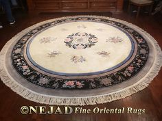 a round rug with fringes on the floor in front of a wooden table and dresser