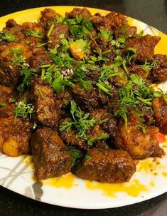 a white plate topped with meat covered in parsley on top of a black table