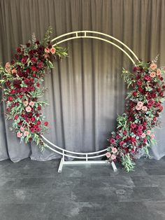 an arch decorated with flowers and greenery for a wedding or event ceremony in front of a curtain