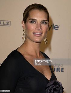 a beautiful woman in black dress posing for the camera at an event with her hand on her hip