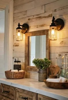 a bathroom vanity with two lights and a basket on it's counter next to a mirror