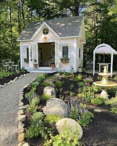 a small white house surrounded by trees and flowers