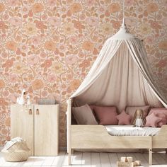 a canopy bed sitting next to a wall with pink and orange floral designs on it