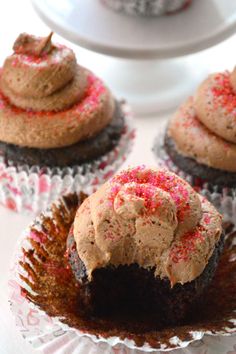 three cupcakes with chocolate frosting and sprinkles are on a plate