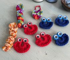 several crocheted items with googly eyes are on the table next to an egg