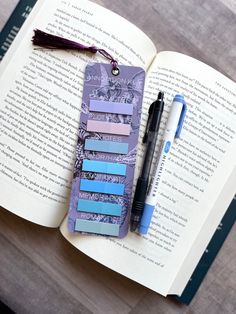 an open book with some sticky notes on it and a pen laying next to it