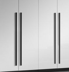 a tall white cabinet with black handles and doors