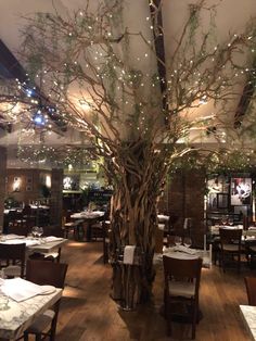 the dining room is decorated with branches and lights, along with white tablecloths