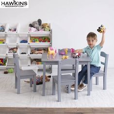 a little boy sitting at a table with toys