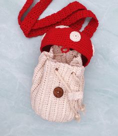 a crocheted bag with a button on the top and a scarf around it