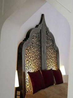 an ornate headboard with red pillows in a bedroom