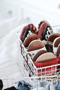 several pairs of slippers in a basket on a bed