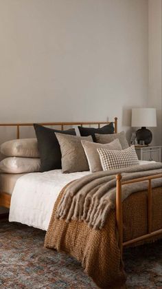 a bed sitting in a bedroom next to a window with pillows on top of it