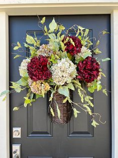 a black front door with a basket and flowers on it