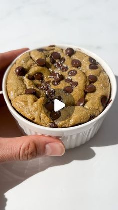 a hand holding a bowl of chocolate chip cookies