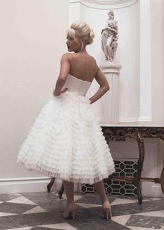 a woman in a white dress is standing near a table